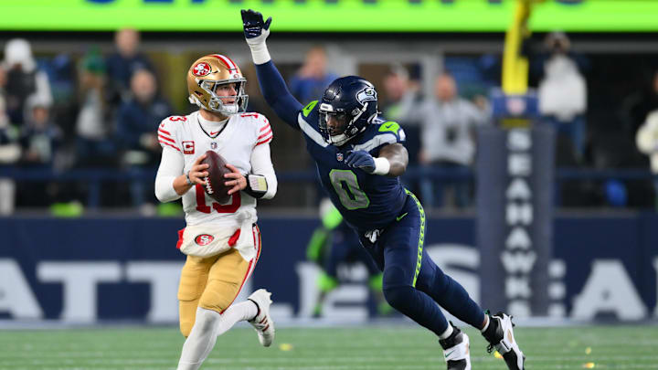San Francisco 49ers quarterback Brock Purdy is pressured by Seattle Seahawks defensive end DeMarcus Lawrence.