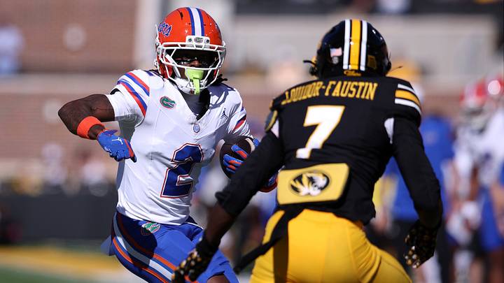 Oct 3, 2026; Columbia, Missouri, USA;  Florida Gators wide receiver Eric Singleton Jr. (2) carries the ball while defended by Missouri Tigers safety Kensley Louidor-Faustin (7) in the first quarter at Faurot Field at Memorial Stadium.  Mandatory Credit: William Purnell-Imagn Images