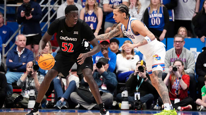 Feb 21, 2026; Lawrence, Kansas, USA; Cincinnati Bearcats center Moustapha Thiam (52) dribbles the ball as Kansas Jayhawks guard Jayden Dawson (1) defends during the second half of the game at Allen Fieldhouse. Mandatory Credit: Denny Medley-Imagn Images