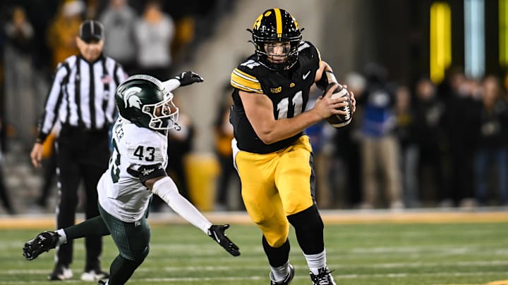 Nov 22, 2025; Iowa City, Iowa, USA; Iowa Hawkeyes quarterback Mark Gronowski (11) scrambles for yards as Michigan State Spartans safety Malik Spencer (43) misses the tackle during the fourth quarter at Kinnick Stadium. Mandatory Credit: Jeffrey Becker-Imagn Images Nov 22, 2025; Iowa City, Iowa, USA; Iowa Hawkeyes quarterback Mark Gronowski (11) scrambles for yards as Michigan State Spartans safety Malik Spencer (43) misses the tackle during the fourth quarter at Kinnick Stadium. Mandatory Credit: Jeffrey Becker-Imagn Images