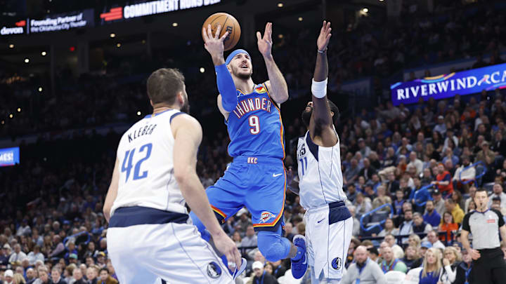 Jan 23, 2025; Oklahoma City, Oklahoma, USA; Oklahoma City Thunder guard Alex Caruso (9) goes up for a basket between Dallas Mavericks guard Kyrie Irving (11) and forward Maxi Kleber (42) during the second half at Paycom Center. Mandatory Credit: Alonzo Adams-Imagn Images