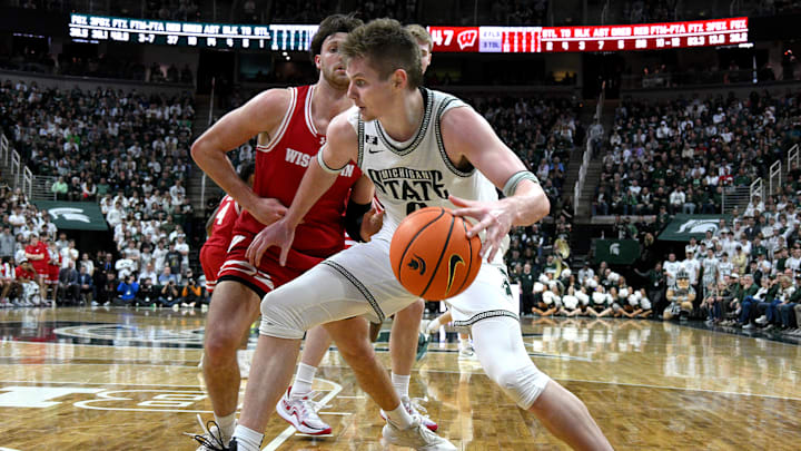  Mar 2, 2025; East Lansing, Michigan, USA;  Michigan State Spartans forward Jaxon Kohler (0) moves the ball down the baseline against Wisconsin Badgers forward Carter Gilmore (7) during the second half at Jack Breslin Student Events Center. Mandatory Credit: Dale Young-Imagn Images