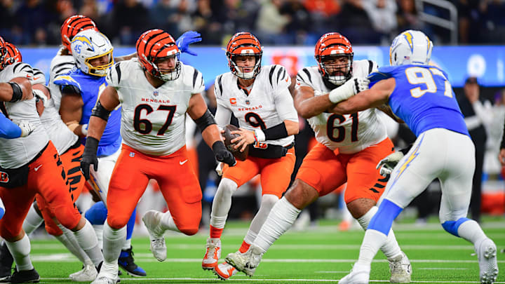 Nov 17, 2024; Inglewood, California, USA; Cincinnati Bengals quarterback Joe Burrow (9) moves out to pass as guard Cody Ford (61) and guard Cordell Volson (67) provide coverage against Los Angeles Chargers linebacker Joey Bosa (97) during the first half at SoFi Stadium. Mandatory Credit: Gary A. Vasquez-Imagn Images