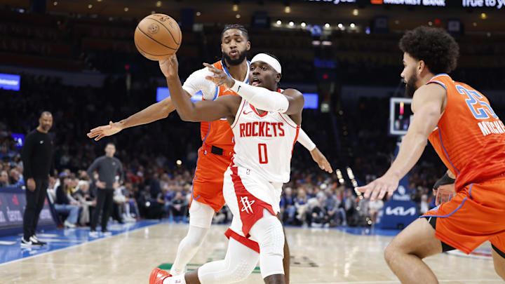 Nov 8, 2024; Oklahoma City, Oklahoma, USA; Houston Rockets guard Aaron Holiday (0) passes the ball between Oklahoma City Thunder guard Isaiah Joe (11) and guard Ajay Mitchell (25) during the second half at Paycom Center. Mandatory Credit: Alonzo Adams-Imagn Images