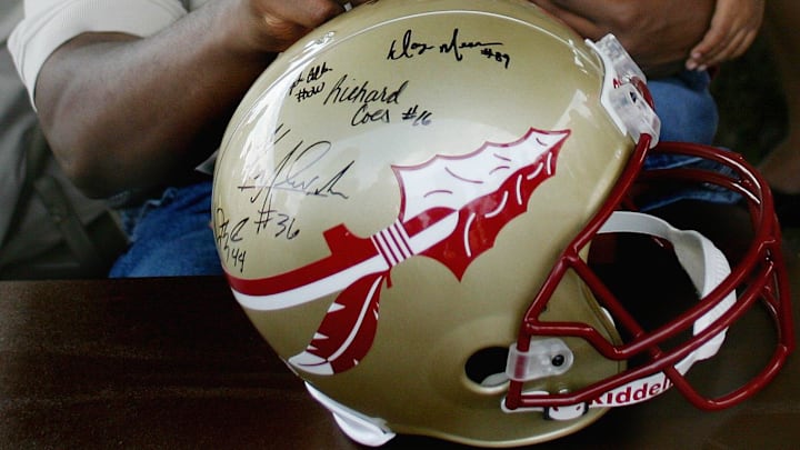 1993; Tallahassee, FL, USA; Former FSU quarterback and 1993 Heisman Trophy winner Charlie Ward signs a Seminole helmet as his son, Caleb, looks on; Mandatory credit: Mike Ewen-USA TODAY NETWORK

