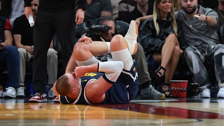 Dec 29, 2025; Miami, Florida, USA; Denver Nuggets center Nikola Jokic (15) holds his knee after an injury against the Miami Heat during the second quarter at Kaseya Center. Mandatory Credit: Sam Navarro-Imagn Images