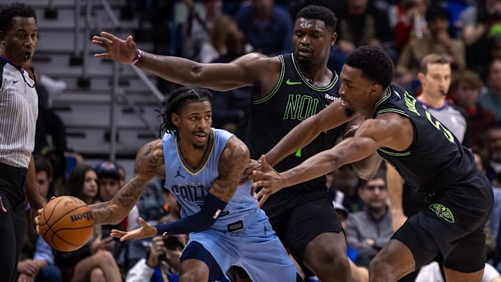 Dec 26, 2023; New Orleans, Louisiana, USA; Memphis Grizzlies guard Ja Morant (12) looks to pass the ball as he is boxed in the corner by New Orleans Pelicans forward Zion Williamson (1) and forward Herbert Jones (5) during the first half at the Smoothie King Center. Mandatory Credit: Stephen Lew-Imagn Images