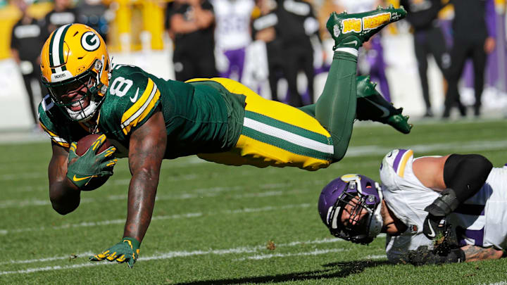 Green Bay Packers running back Josh Jacobs (8) dives for yardage against Minnesota Vikings linebacker Blake Cashman.