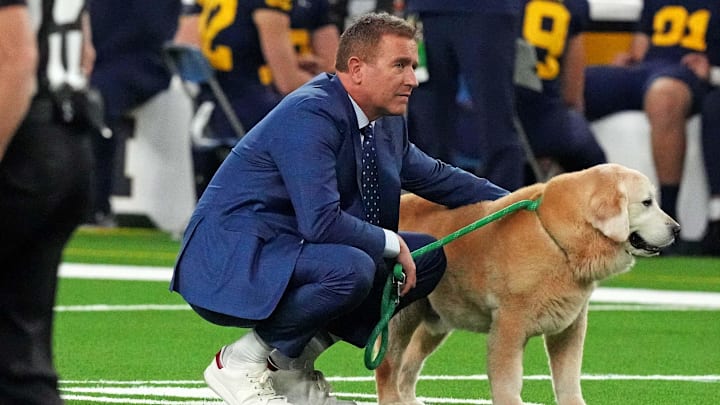 ESPN analyst Kirk Herbstreit walks his dog Ben before the 2024 College Football Playoff national championship game between the Michigan Wolverines and the Washington Huskies at NRG Stadium on January 8, 2024. ESPN analyst Kirk Herbstreit walks his dog Ben before the 2024 College Football Playoff national championship game between the Michigan Wolverines and the Washington Huskies at NRG Stadium on January 8, 2024.