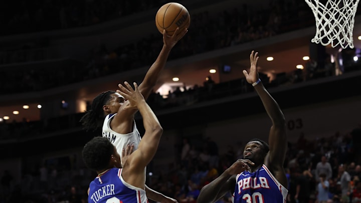 Oct 11, 2024; Des Moines, Iowa, USA; Minnesota Timberwolves guard Rob Dillingham (4) drives between Philadelphia 76ers forward Jordan Tucker (22) and Philadelphia 76ers center Adem Bona (30) at Wells Fargo Arena. The Timberwolves beat the 76ers 121 to 111.  Mandatory Credit: Reese Strickland-Imagn Images