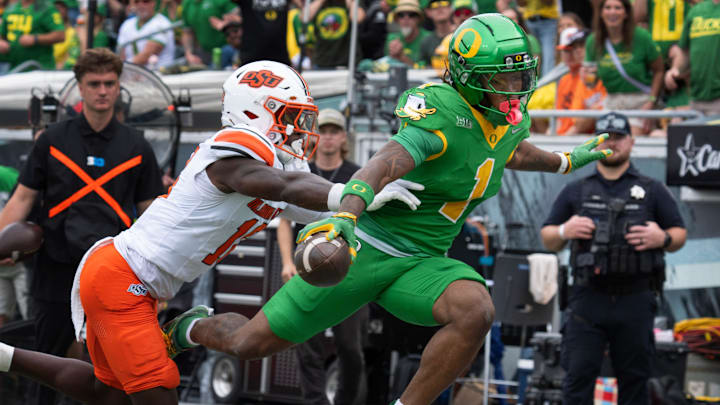 Oregon’s Dakorien Moore, right, flies over the goal line ahead of Oklahoma State’s David Kabongo for a second quarter touchdown at Autzen.