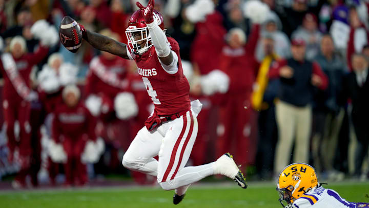 Oklahoma Sooners wide receiver Deion Burks (4) leaps to the end zone past Louisiana State Tigers cornerback PJ Woodland (11) to score a touchdown during a college football game between the University of Oklahoma Sooners (OU) and the LSU Tigers at Gaylord Family – Oklahoma Memorial Stadium in Norman, Okla., Saturday, Nov. 29, 2025. Oklahoma won 17-13.