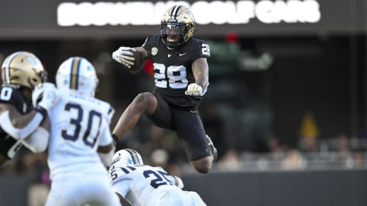 Aug 30, 2025; Nashville, Tennessee, USA;  Vanderbilt Commodores running back Sedrick Alexander (28) hurdles over Charleston Southern Buccaneers cornerback Jayden Hancock (30) during the first half at FirstBank Stadium. Mandatory Credit: Steve Roberts-Imagn Images