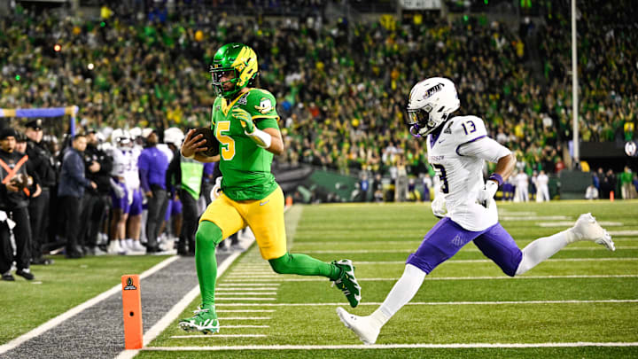 Dec 20, 2025; Eugene, OR, USA; Oregon Ducks quarterback Dante Moore (5) rushes for a touchdown as James Madison Dukes safety Tyler Brown (13) defends during the first quarter at Autzen Stadium. Mandatory Credit: Troy Wayrynen-Imagn Images