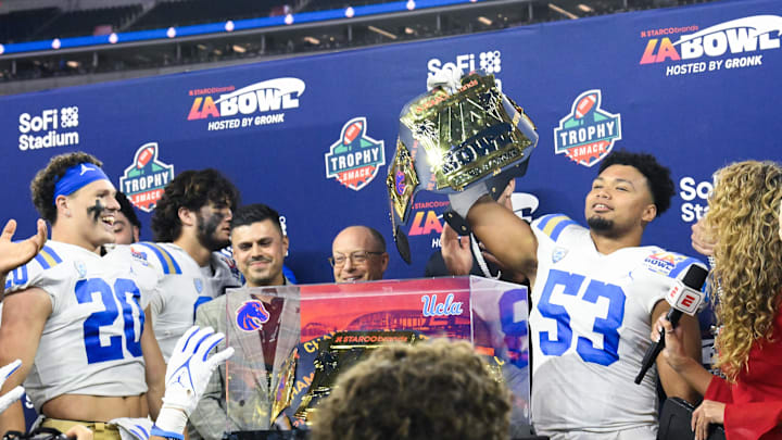 Dec 16, 2023; Inglewood, CA, USA; UCLA Bruins linebacker Darius Muasau (53) holds up the award for defensive player of the game after defeating the Boise State Broncos in the Starco Brands LA Bowl at SoFi Stadium. Mandatory Credit: Robert Hanashiro-Imagn Images