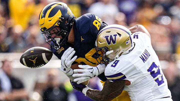 Linebacker Jacob Manu separates Michigan tight end Deakon Tonielli from the football in the first half in Ann Arbor.