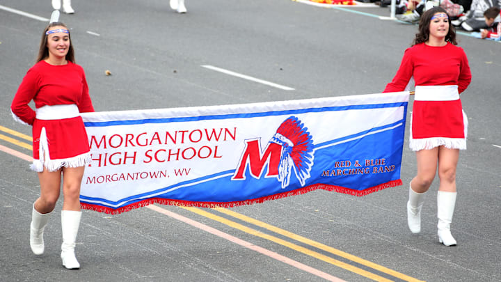 A pair of Morgantown High School students hold a banner during the band's performance at the 124th Rose Parade Presented By Honda. Daughters of WVU basketball coaches Darian DeVries and Mark Kellogg currently star for the Morgantown High School girls' basketball team.