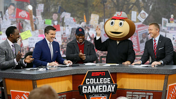 Lee Corso waves while wearing a Brutus Buckeye head as, from left, Desmond Howard, Rece Davis, Archie Griffin, and Kirk Herbstreit applaud his pick during ESPN's College GameDay broadcast from the campus of Ohio State prior to the NCAA football game against the Michigan State Spartans in Columbus on Nov. 21, 2015.