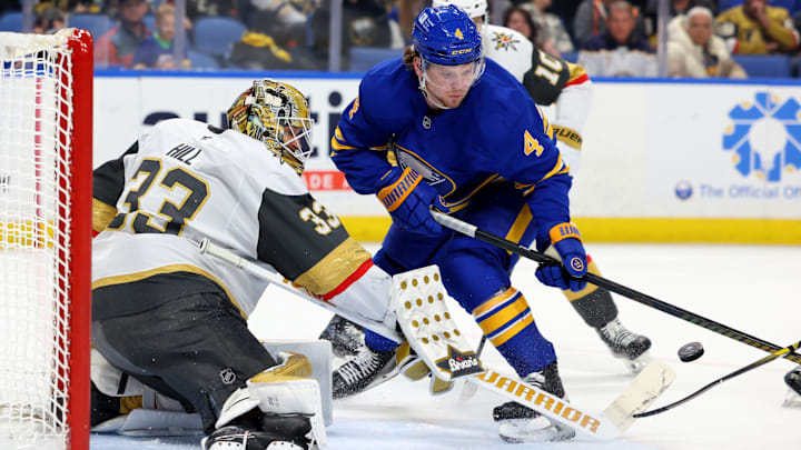 Mar 15, 2025; Buffalo, New York, USA;  Vegas Golden Knights goaltender Adin Hill (33) looks to make a save as Buffalo Sabres defenseman Bowen Byram (4) looks for the rebound during the third period at KeyBank Center. Mandatory Credit: Timothy T. Ludwig-Imagn Images