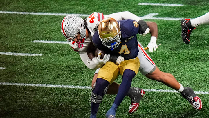 Ohio State Buckeyes defensive end JT Tuimoloau (44) tackles Notre Dame Fighting Irish running back Jeremiyah Love (4) during the College Football Playoff championship at Mercedes-Benz Stadium in Atlanta on Jan. 20, 2025.