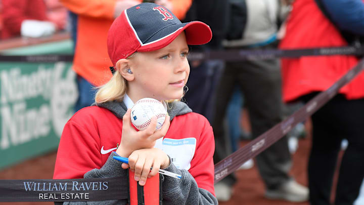 A young Boston Red Sox fan waits for players to walk by in hopes of getting a ball autographed before a game against the San Francisco Giants at Fenway Park.