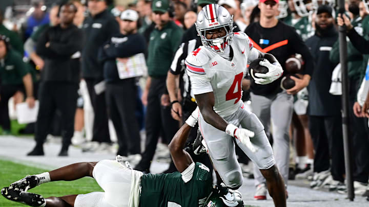 Sep 28, 2024; East Lansing, Michigan, USA;  Ohio State Buckeyes wide receiver Jeremiah Smith (4) runs past Michigan State Spartans defensive back Ed Woods (4) in the first quarter at Spartan Stadium. Mandatory Credit: Dale Young-Imagn Images