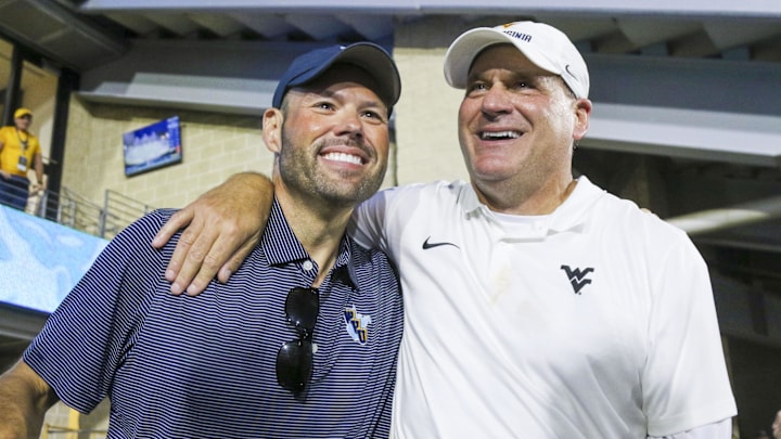 Sep 13, 2025; Morgantown, West Virginia, USA; West Virginia Mountaineers head coach Rich Rodriguez celebrates with West Virginia University athletic director Wren Baker after defeating the Pittsburgh Panthers at Milan Puskar Stadium. Mandatory Credit: Ben Queen-Imagn Images