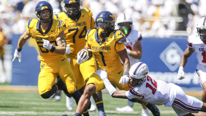 Aug 30, 2025; Morgantown, West Virginia, USA; West Virginia Mountaineers running back Jahiem White (1) runs the ball and is tackled by Robert Morris Colonials quarterback Jake Wolfe (12) during the first quarter at Milan Puskar Stadium. Mandatory Credit: Ben Queen-Imagn Images