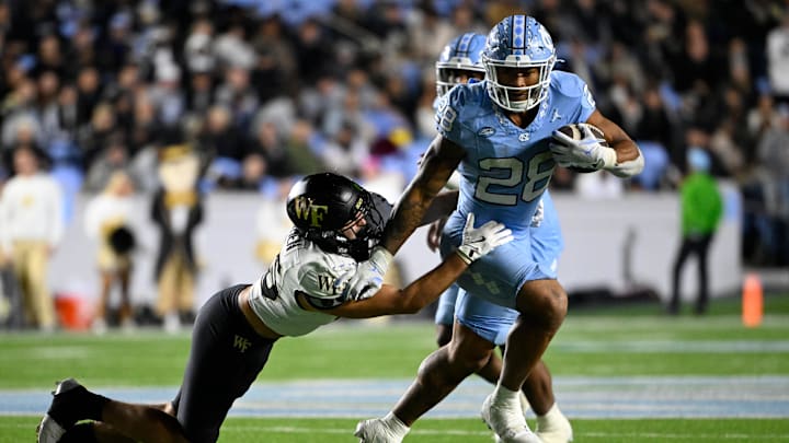 Nov 16, 2024; Chapel Hill, North Carolina, USA;  North Carolina Tar Heels running back Omarion Hampton (28) runs as Wake Forest Demon Deacons defensive back Nick Andersen (45) defends in the third quarter at Kenan Memorial Stadium. Mandatory Credit: Bob Donnan-Imagn Images