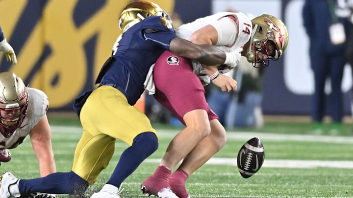 Nov 9, 2024; South Bend, Indiana, USA; Florida State Seminoles quarterback Luke Kromenhoek (14) is sacked by Notre Dame Fighting Irish linebacker Jaylen Sneed (3) in the third quarter at Notre Dame Stadium. Mandatory Credit: Matt Cashore-Imagn Images