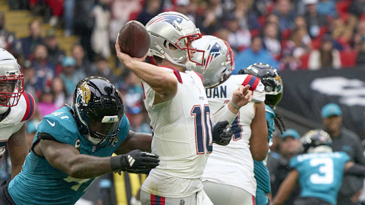 Oct 20, 2024; London, United Kingdom; New England Patriots quarterback Drake Maye (10) throws the ball under pressure from Jacksonville Jaguars defensive end Josh Hines-Allen (41)  in the first half during an NFL International Series game at Wembley Stadium. 
