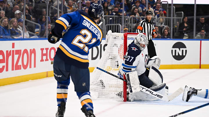 May 2, 2025; St. Louis, Missouri, USA; St. Louis Blues right wing Jimmy Snuggerud (21) is unable to score past Winnipeg Jets goaltender Connor Hellebuyck (37) during the second period in game six of the first round of the 2025 Stanley Cup Playoffs at Enterprise Center. Mandatory Credit: Connor Hamilton-Imagn Images