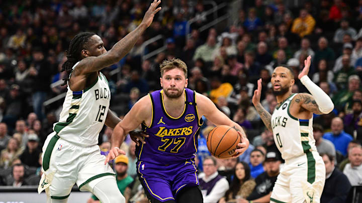 Mar 13, 2025; Milwaukee, Wisconsin, USA; Los Angeles Lakers guard Luka Doncic (77) drives to the basket between Milwaukee Bucks guard Taurean Prince (12) and guard Damian Lillard (0) in the third quarter at Fiserv Forum. Mandatory Credit: Benny Sieu-Imagn Images