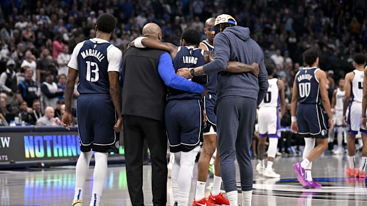 Dallas Mavericks guard Kyrie Irving is helped off the court by forward Naji Marshall and forward Anthony Davis.