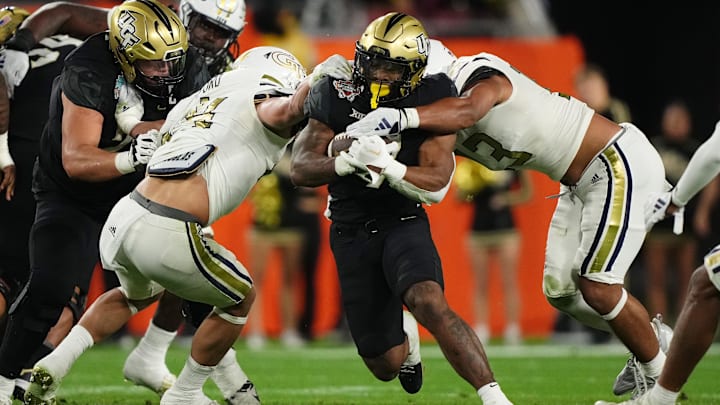 Dec 22, 2023; Tampa, FL, USA; UCF Knights running back RJ Harvey (7) runs the ball between Georgia Tech Yellow Jackets linebacker Kyle Efford (44) and linebacker Paul Moala (13) during the first half of the Gasparilla Bowl at Raymond James Stadium. Mandatory Credit: Jasen Vinlove-USA TODAY Sports
