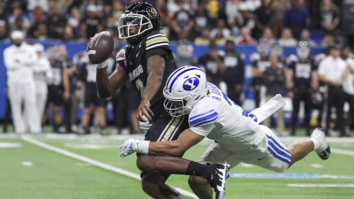 Dec 28, 2024; San Antonio, TX, USA; Colorado Buffaloes quarterback Shedeur Sanders (2) is tackled by Brigham Young Cougars safety Raider Damuni (3) during the second quarter at Alamodome. Mandatory Credit: Troy Taormina-Imagn Images