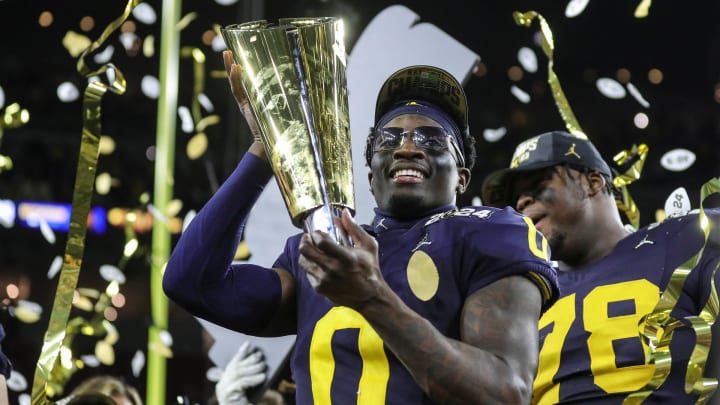 Michigan defensive back Mike Sainristil lifts the trophy to celebrate the 34-13 win over Washington