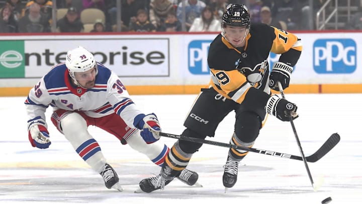 Feb 23, 2025; Pittsburgh, Pennsylvania, USA;  Pittsburgh Penguins center Cody Glass (19) moves the puck New York Rangers center Sam Carrick (39) during the first period against at PPG Paints Arena. Mandatory Credit: Charles LeClaire-Imagn Images