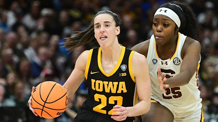 Iowa Hawkeyes guard Caitlin Clark (22) dribbles the ball past South Carolina Gamecocks guard Raven Johnson (25) 