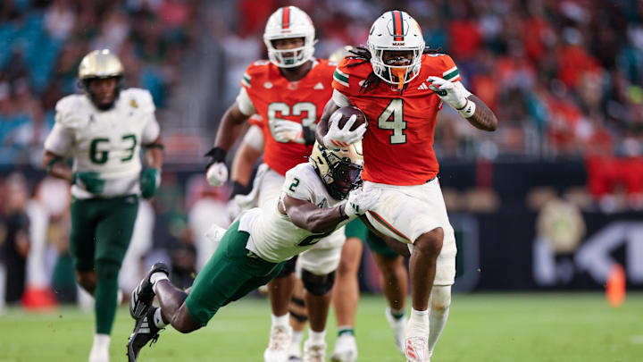 Sep 13, 2025; Miami Gardens, Florida, USA; Miami Hurricanes running back Mark Fletcher Jr. (4) breaks a tackle from South Florida Bulls safety Tavin Ward (2) to score touchdown in the second quarter  at Hard Rock Stadium. Mandatory Credit: Nathan Ray Seebeck-Imagn Images