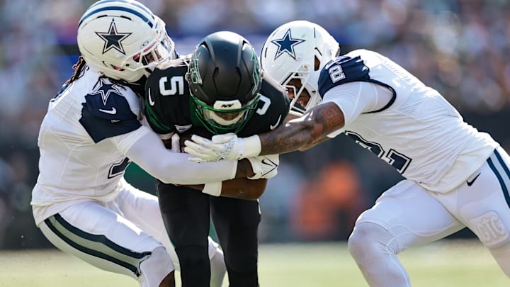 New York Jets wide receiver Garrett Wilson is tackled by Dallas Cowboys cornerback Trevon Diggs and safety Juanyeh Thomas.