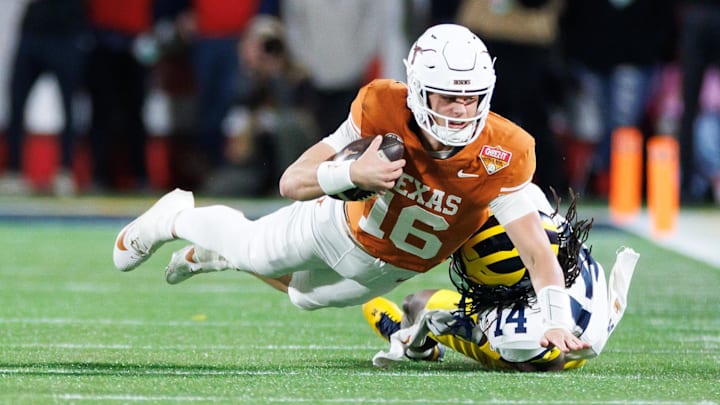 Texas Longhorns quarterback Arch Manning (16) reaches with the ball for a first down while Michigan Wolverines defensive back Jordan Young (14) attempts to tackle during the second half at Camping World Stadium.