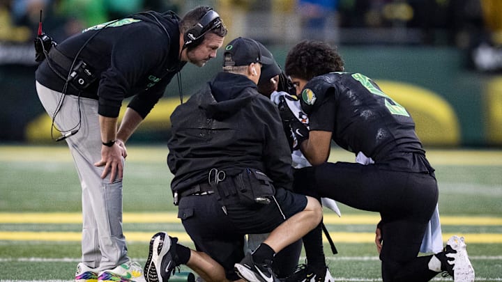 Oregon head coach Dan Lanning, left, checks on injured quarterback Dante Moore at the start of the first half as the Oregon Ducks host the Wisconsin Badgers on Oct. 25, 2025, at Autzen Stadium in Eugene, Oregon.
