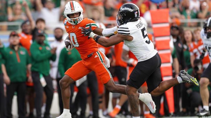 Dec 28, 2024; Orlando, FL, USA; Miami Hurricanes wide receiver Joshisa Trader (0) holds off Iowa State Cyclones defensive back Myles Purchase (5) in the second quarter during the Pop Tarts bowl at Camping World Stadium. Mandatory Credit: Nathan Ray Seebeck-Imagn Images