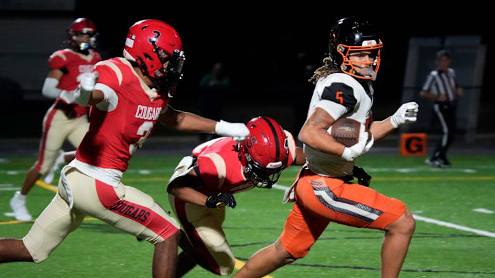 Cocoa High wide receiver Jayvan Boggs (#5) is pursued by Cardinal Mooney High defensive backs Macaiden Brown (#3) and Colton Davis (#5) as he heads toward the end zone in the first quarter. Cocoa High School defeated Cardinal Mooney Catholic High School 31-21 to win the Class 2A semi-final game Friday night in Sarasota.