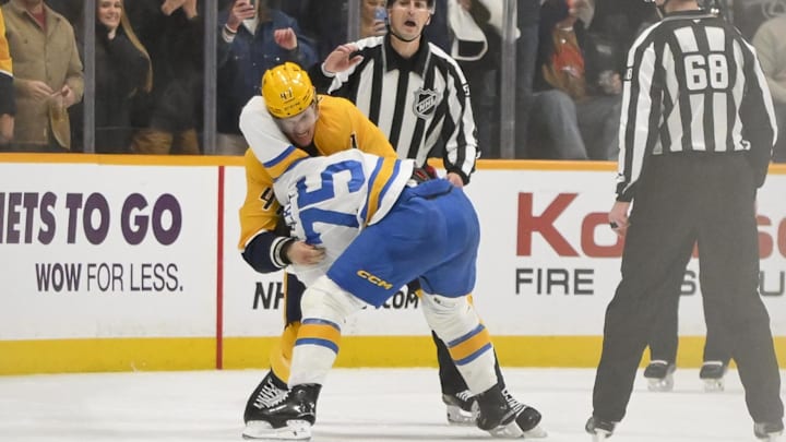 Dec 11, 2025; Nashville, Tennessee, USA;  St. Louis Blues defenseman Tyler Tucker (75) and Nashville Predators right wing Michael McCarron (47) exchange blows during the second period at Bridgestone Arena. Mandatory Credit: Steve Roberts-Imagn Images