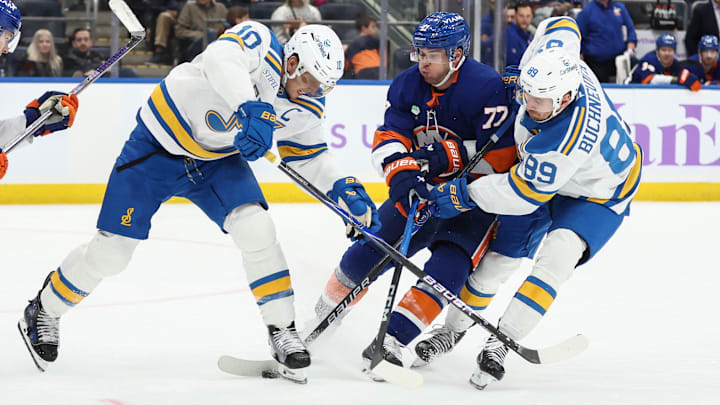 Nov 22, 2025; Elmont, New York, USA;  New York Islanders defenseman Tony Deangelo (77) battles for control of the puck with St. Louis Blues center Brayden Schenn (10) and  left wing Pavel Buchnevich (89) in the third period at UBS Arena. Mandatory Credit: Wendell Cruz-Imagn Images