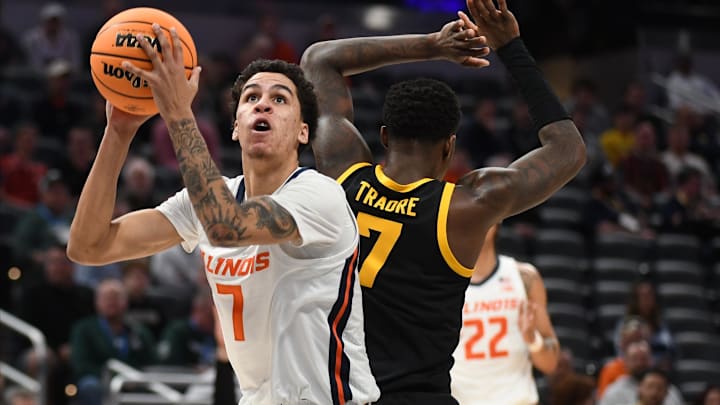 Mar 13, 2025; Indianapolis, IN, USA; Illinois Fighting Illini forward Will Riley (7) scores past Iowa Hawkeyes forward Seydou Traore (7) during the first half at Gainbridge Fieldhouse. Mandatory Credit: Robert Goddin-Imagn Images