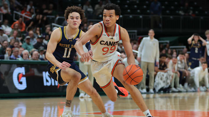 Feb 1, 2025; Coral Gables, Florida, USA; Miami Hurricanes guard Divine Ugochukwu (99) drives to the basket past Notre Dame Fighting Irish guard Braeden Shrewsberry (11) during the second half at Watsco Center. Mandatory Credit: Sam Navarro-Imagn Images