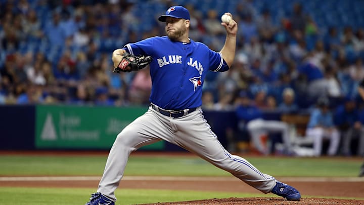 Toronto Blue Jays pitcher Mark Buehrle throws a pitch off a mound in a blue jersey, a blue hat and gray pants.